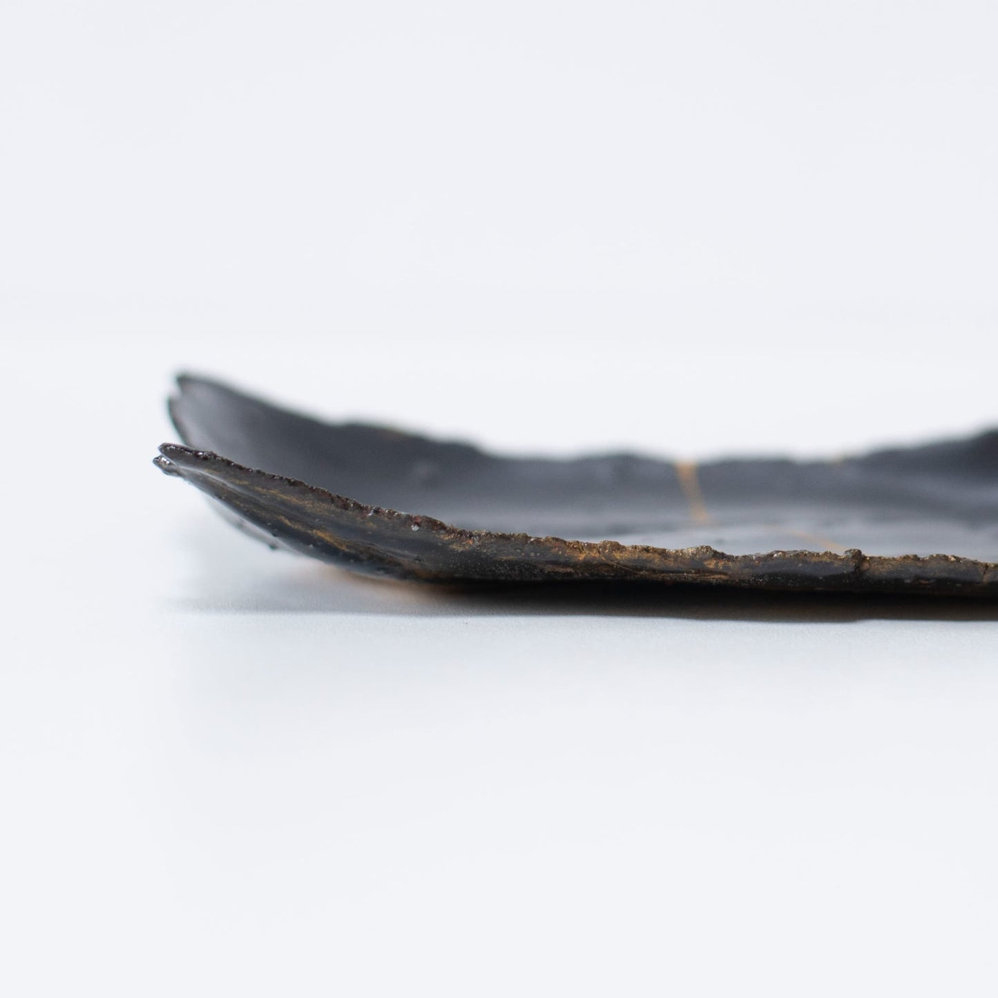 Close-up of the side profile of Kintsugi Plate "Tenmoku" Black 01, highlighting the texture.