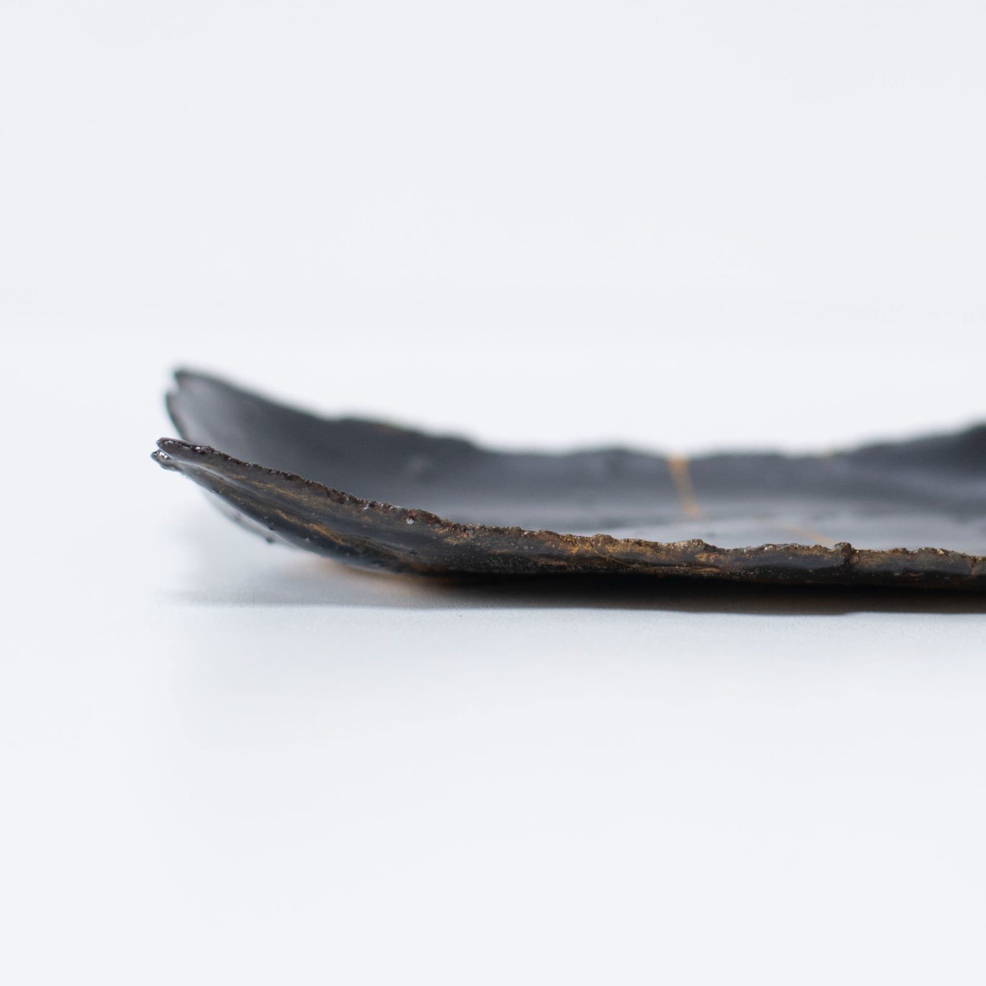 Close-up of the side profile of Kintsugi Plate "Tenmoku" Black 01, highlighting the texture.