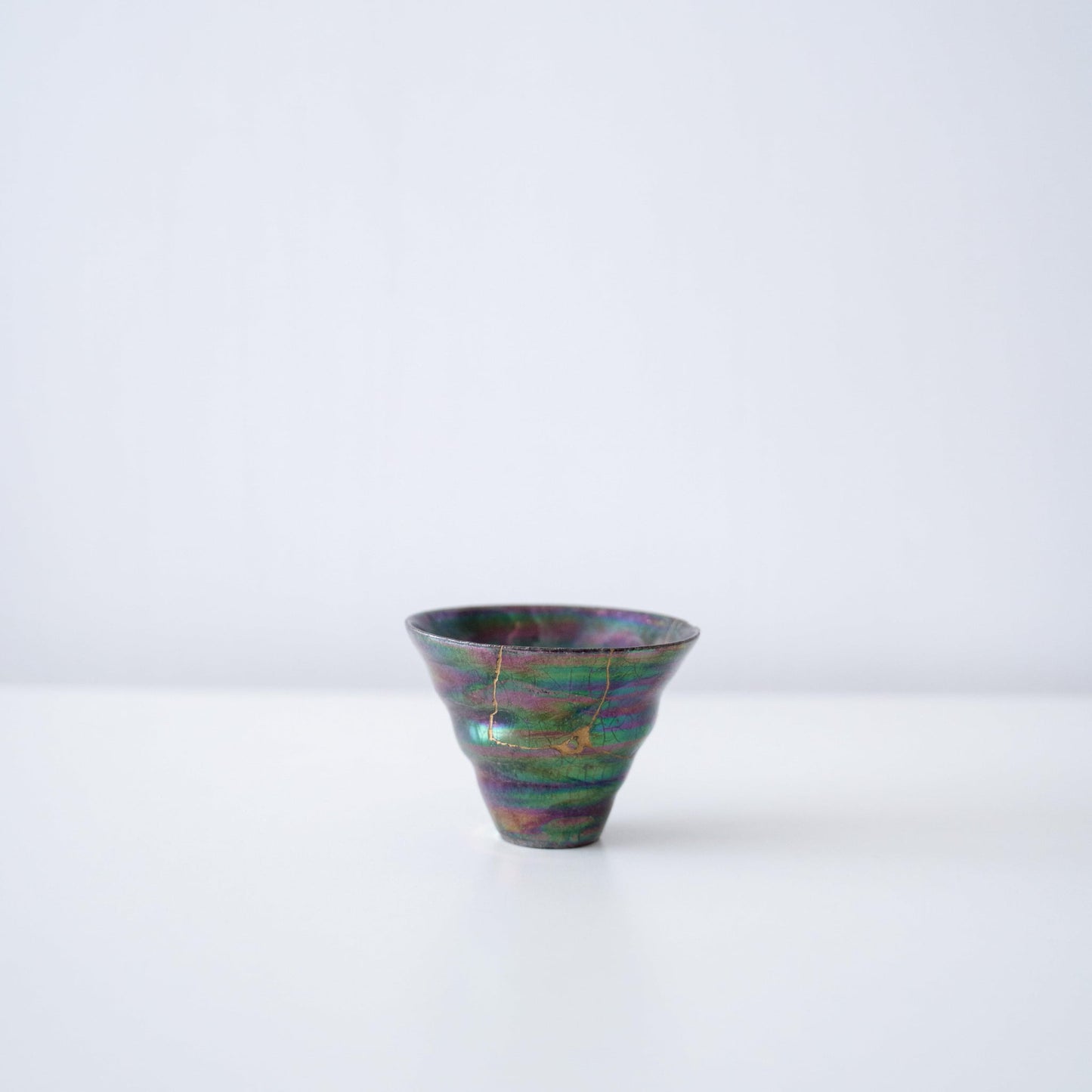 Side view of Kintsugi Sake Cup "Colored Clay Luster" in a white background