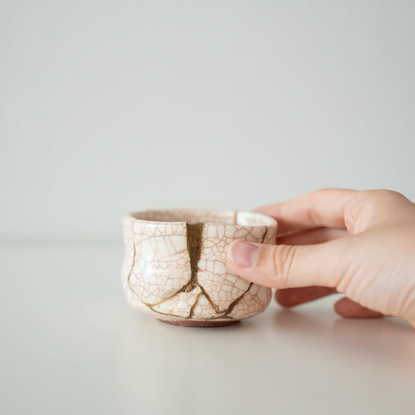 Hand holding Kintsugi Tea Bowl "Vermilion Crackle", showing its size and how it fits in the hand