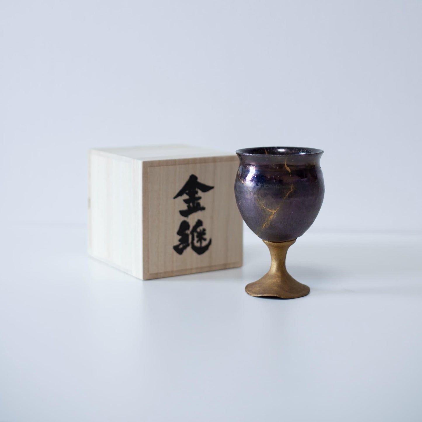 Magenta kintsugi wine goblet repaired with Kintsugi, a traditional Japanese technique, presented in a paulownia wood box with the inscription "Kintsugi".