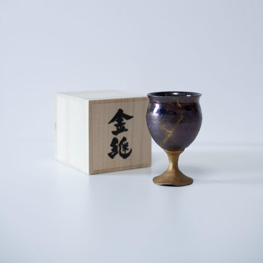 Magenta kintsugi wine goblet repaired with Kintsugi, a traditional Japanese technique, presented in a paulownia wood box with the inscription "Kintsugi".