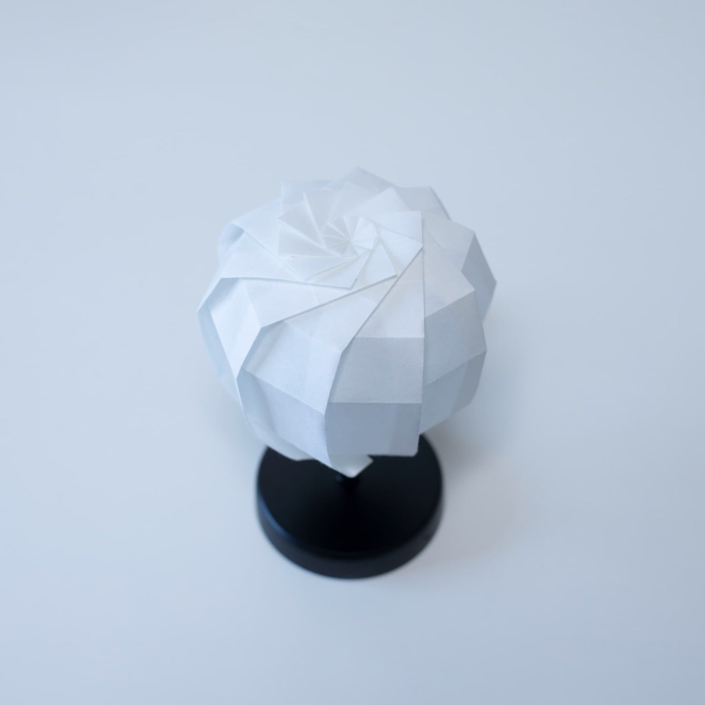 Origami Table lamp "maru" with a black stand and a spherical white lampshade crafted from intricately folded washi paper.