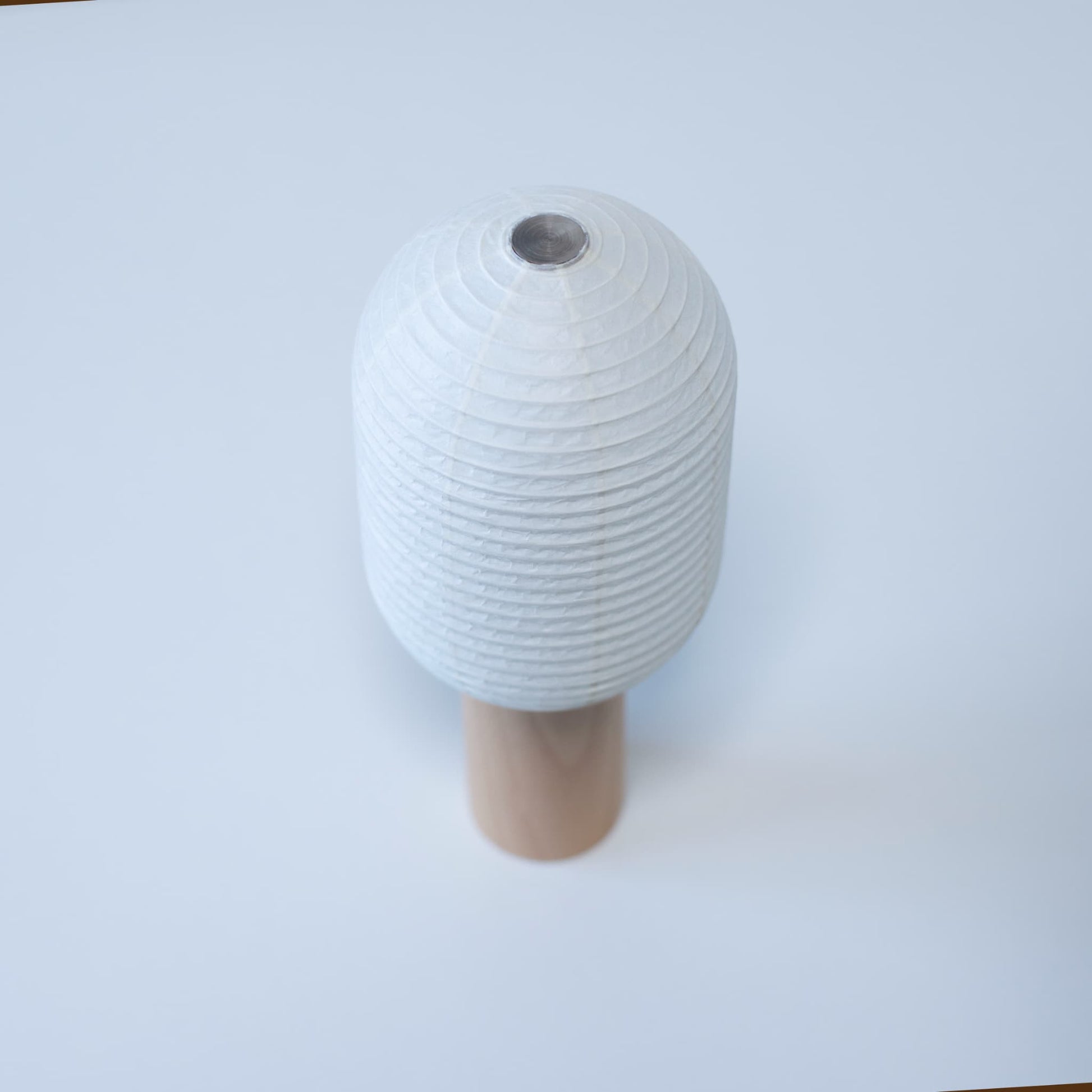 Japanese paper lamp "TORCHIN VERTICAL" featuring a tall, cylindrical white washi paper shade and a wooden handle, handcrafted in Yame, Fukuoka, Japan.