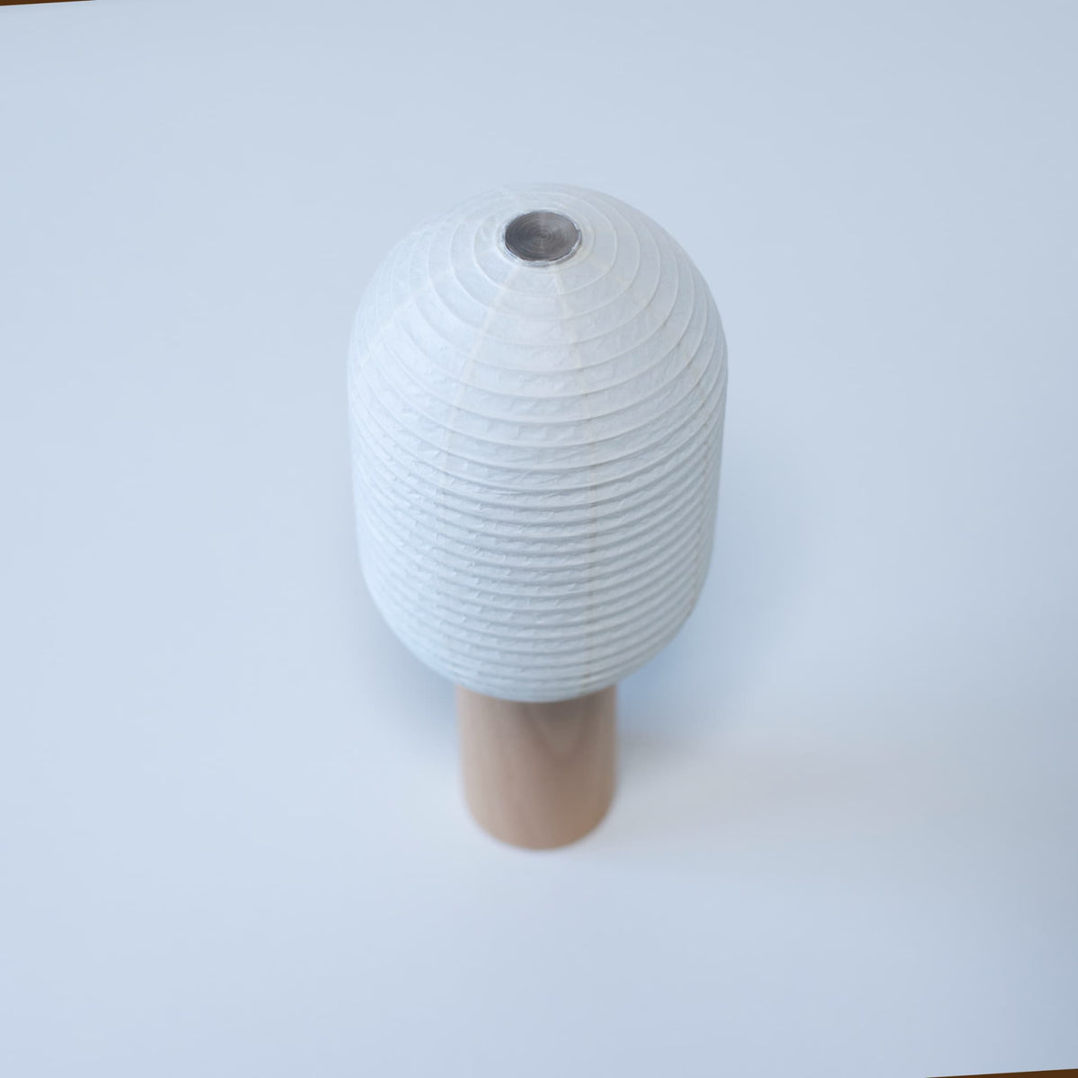 Japanese paper lamp "TORCHIN VERTICAL" featuring a tall, cylindrical white washi paper shade and a wooden handle, handcrafted in Yame, Fukuoka, Japan.