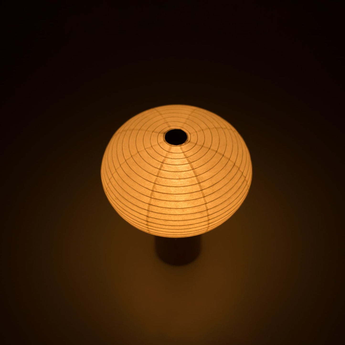 Paper table lamp "TORCHIN OVAL" emitting a warm glow, handcrafted in Yame, Fukuoka, Japan, known for its traditional Yame lanterns.
