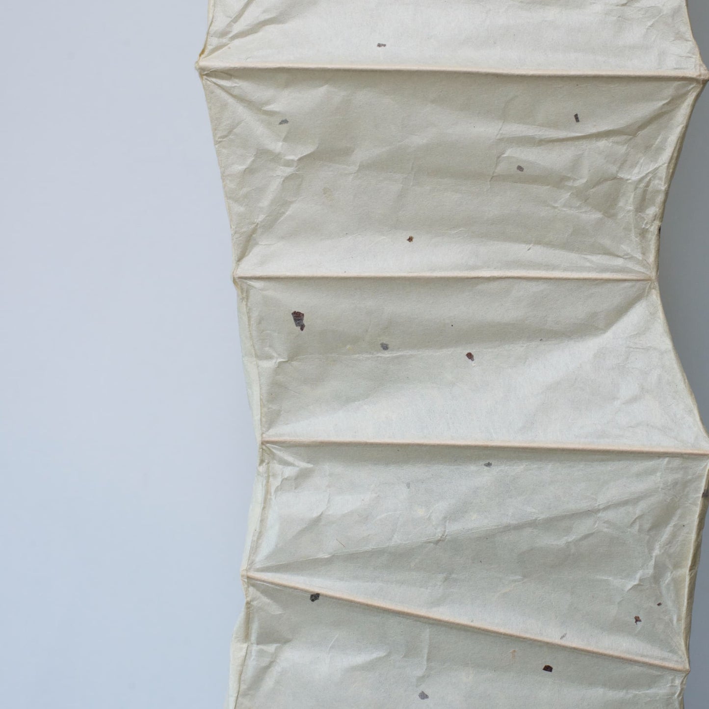 Detailed side view of a curved Japanese washi paper lamp on a white background, showcasing the patterns of the washi