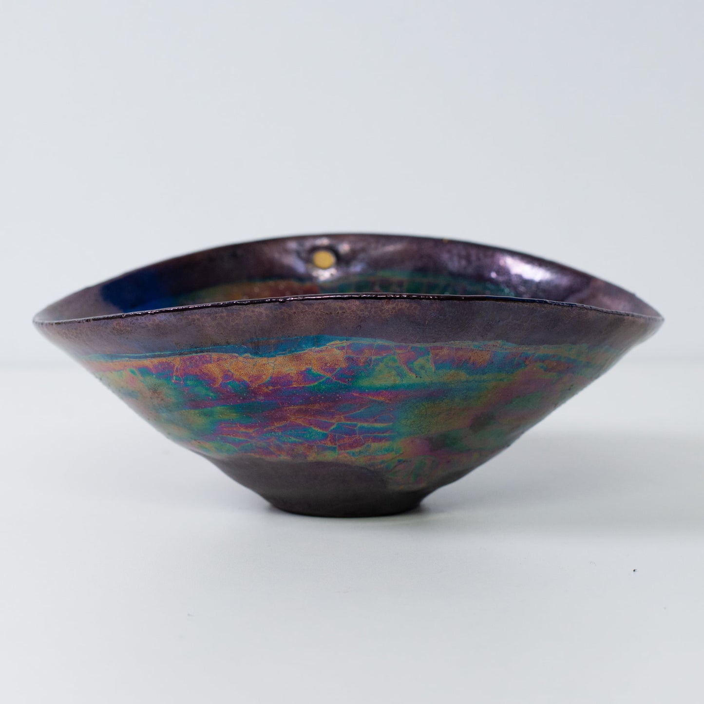 Japanese Kintsugi pottery bowl side view with metallic glaze and gold-filled cracks