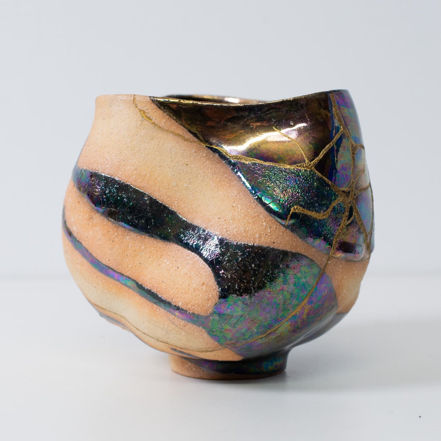 Side view of kintsugi pottery matcha bowl with golden seams and natural wabi-sabi form