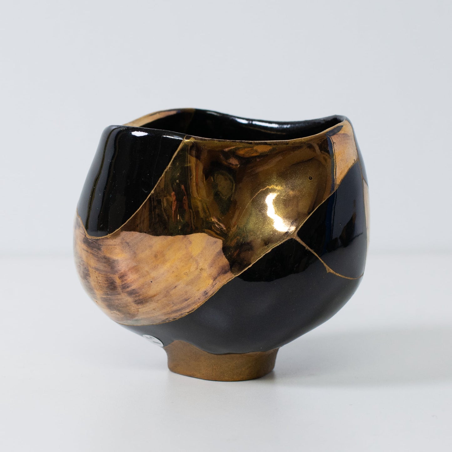 Side view of kintsugi pottery bowl featuring gold repair lines and deep contrast glaze