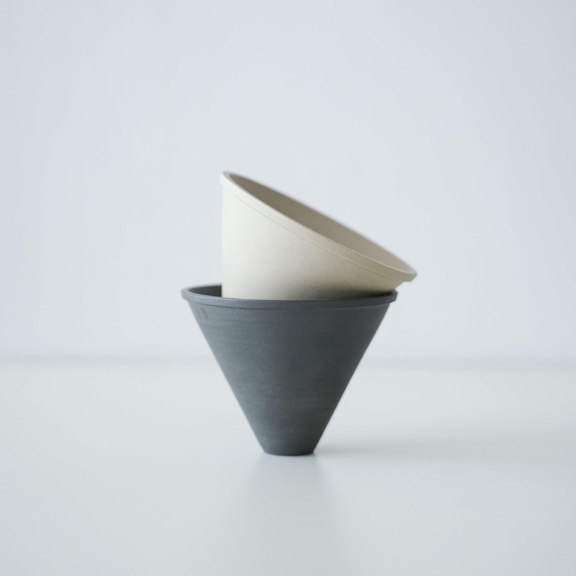 A stack of minimalist black and white Banko ware coffee drippers.