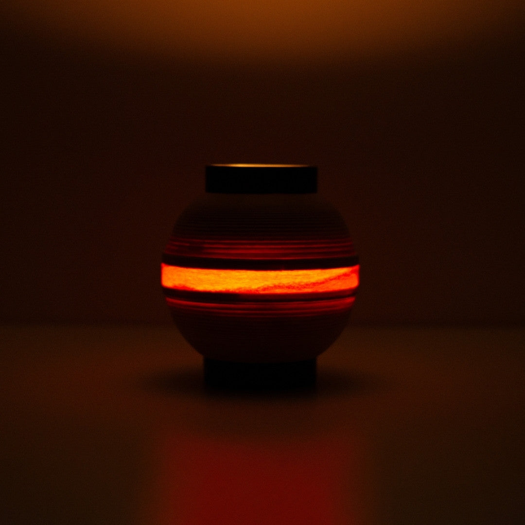 Japanese table lamp with glowing ring of light, casting a flame-like hue for ambient interiors.