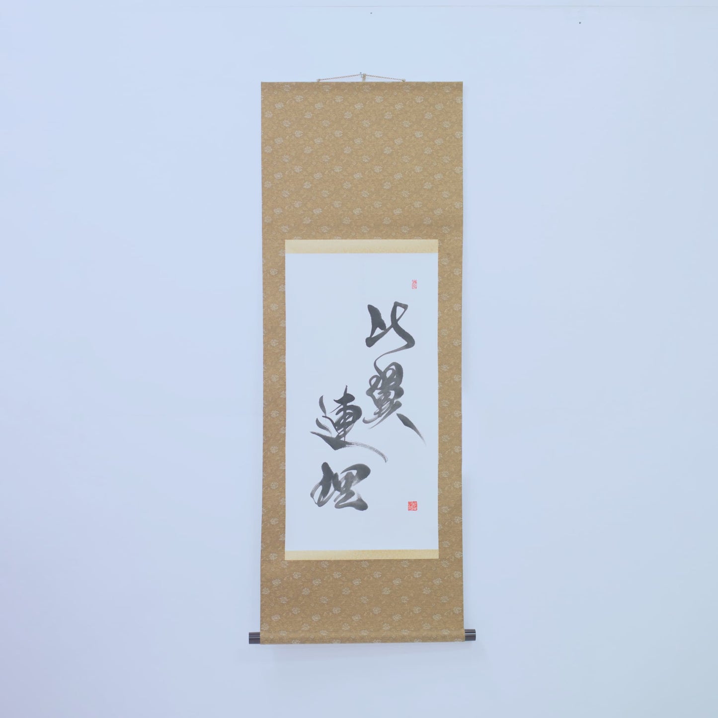 Japanese scroll featuring calligraphy of Hiyoku Renri on white wall