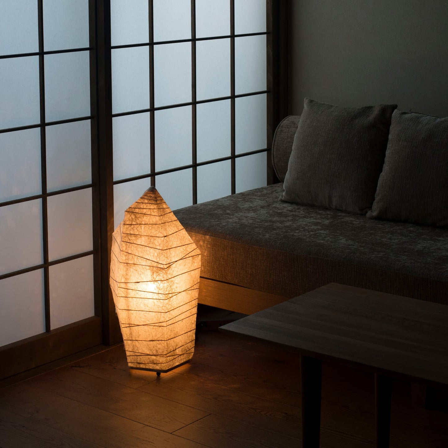 Japanese paper floor lamp with ice stone design emitting warm light, captured from an overhead angle in a traditional Japanese room.