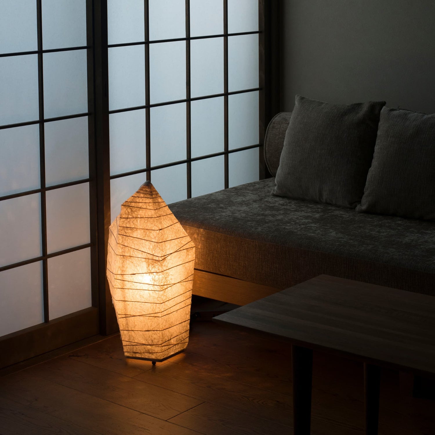 Japanese paper floor lamp with ice stone design emitting warm light, captured from an overhead angle in a traditional Japanese room.