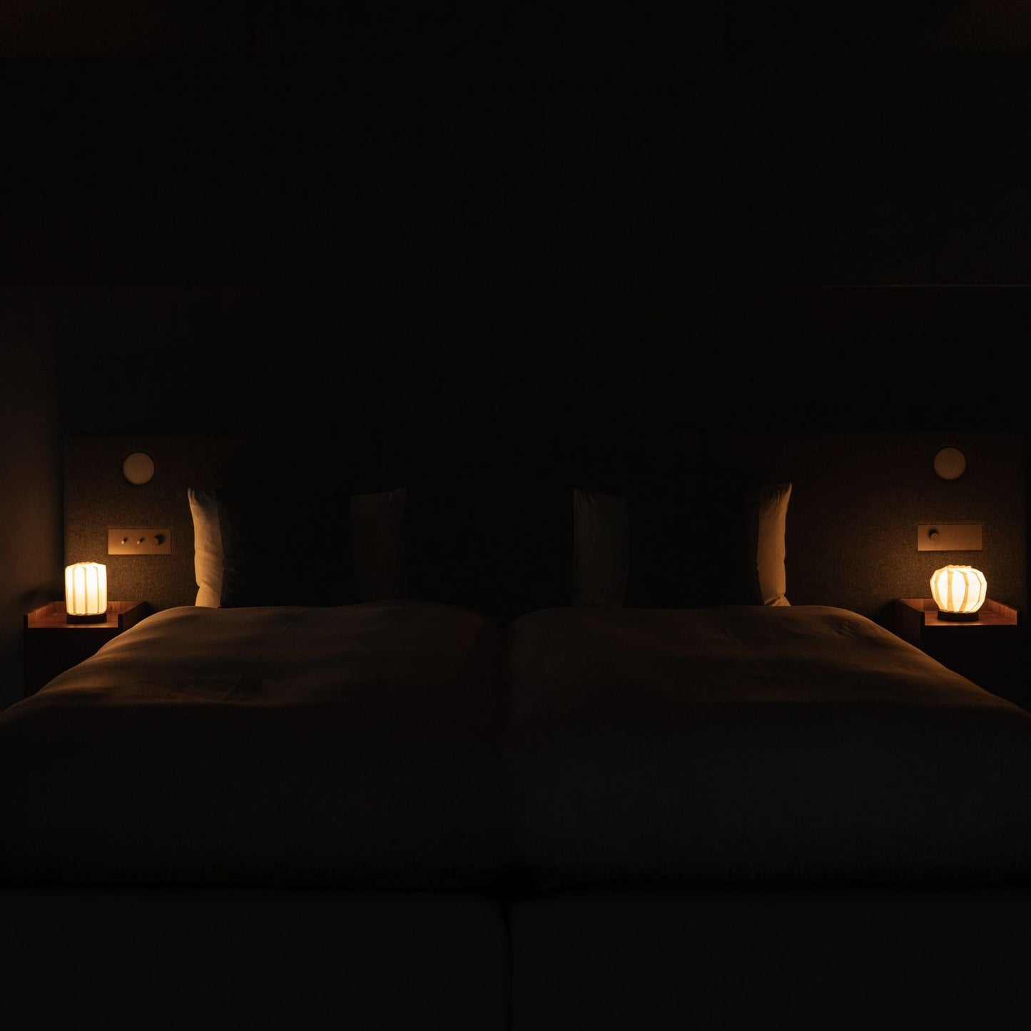 Japanese Paper Table Lamp "Flower of Light M" lit on a wooden bedside table