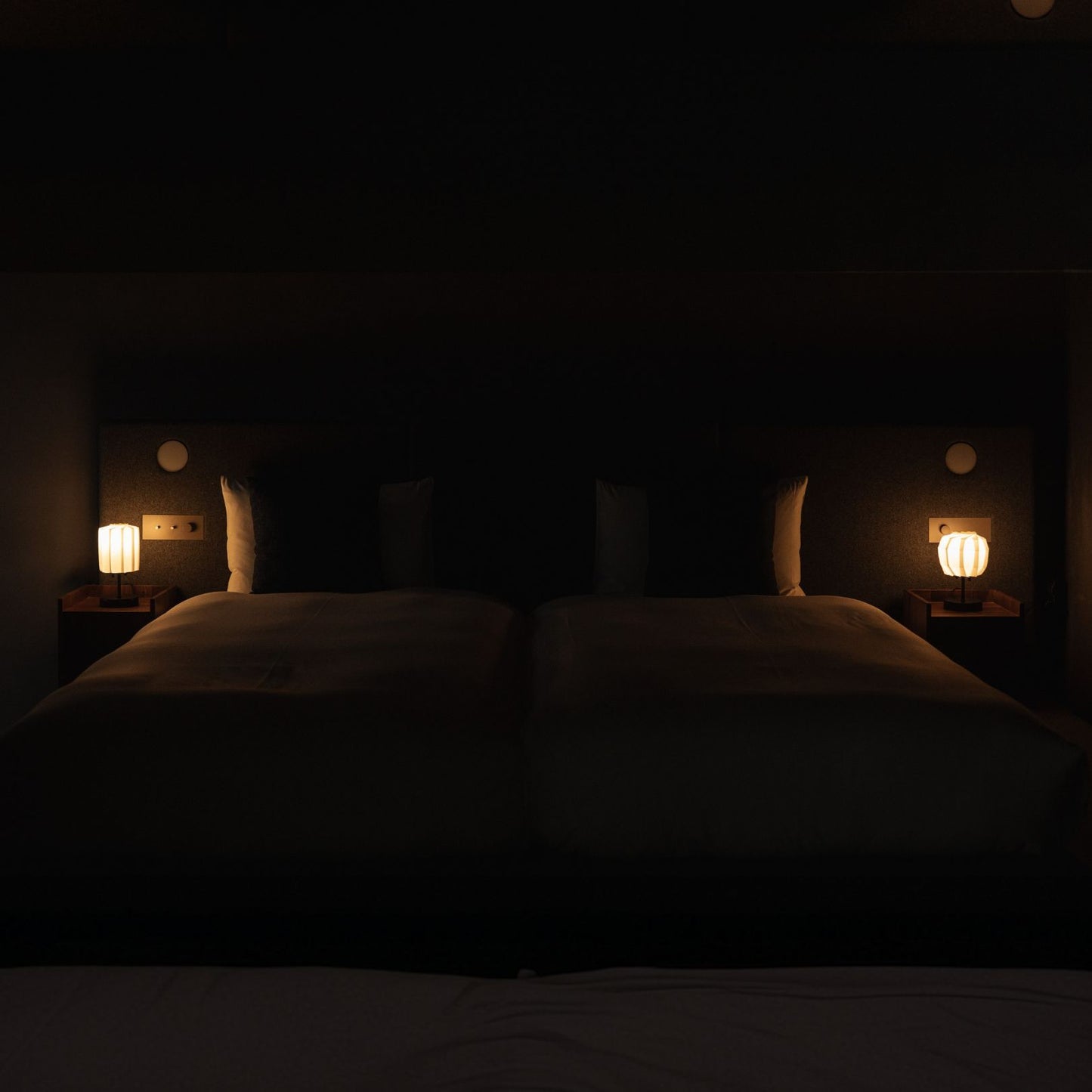 Japanese Paper Table Lamp "Flower of Light" lit on a wooden bedside table