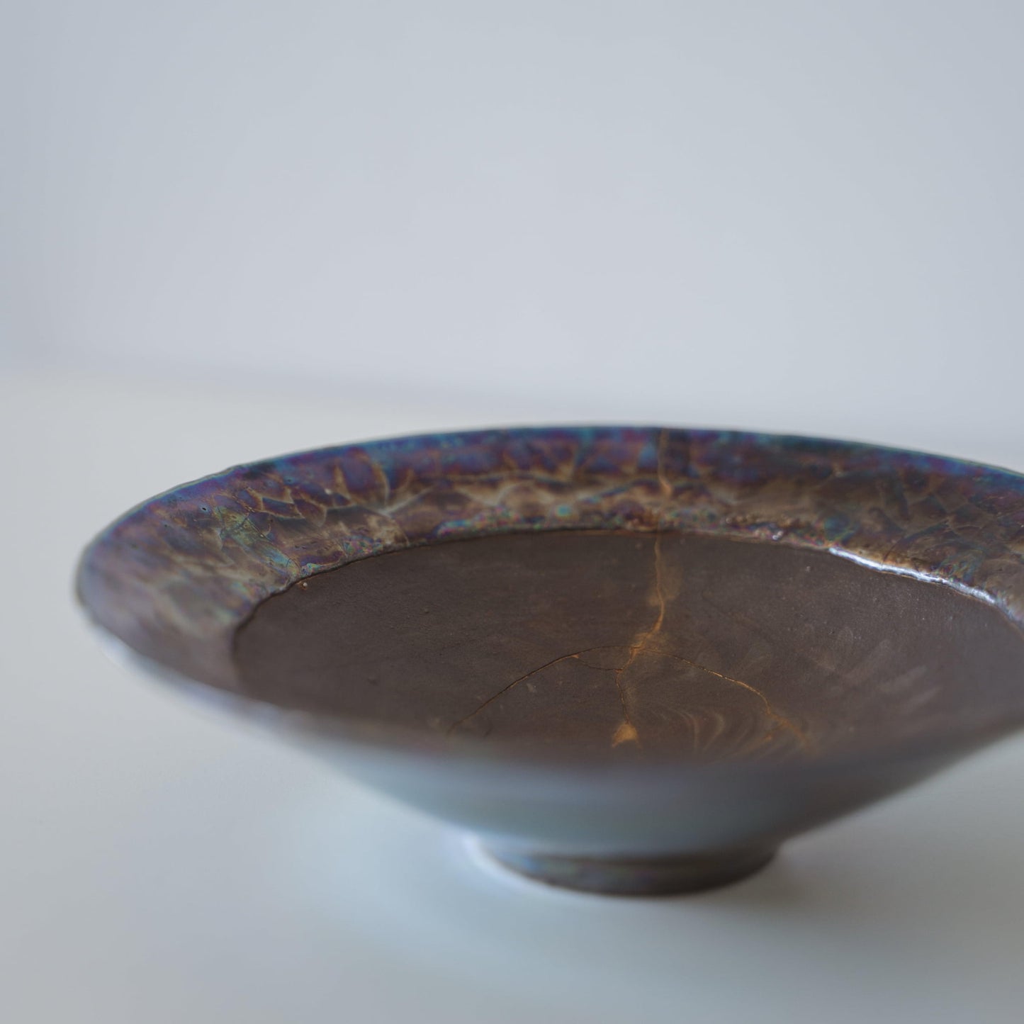 Japanese Kintsugi bowl in deep brown with a gold repair, showcasing the beauty of imperfection.