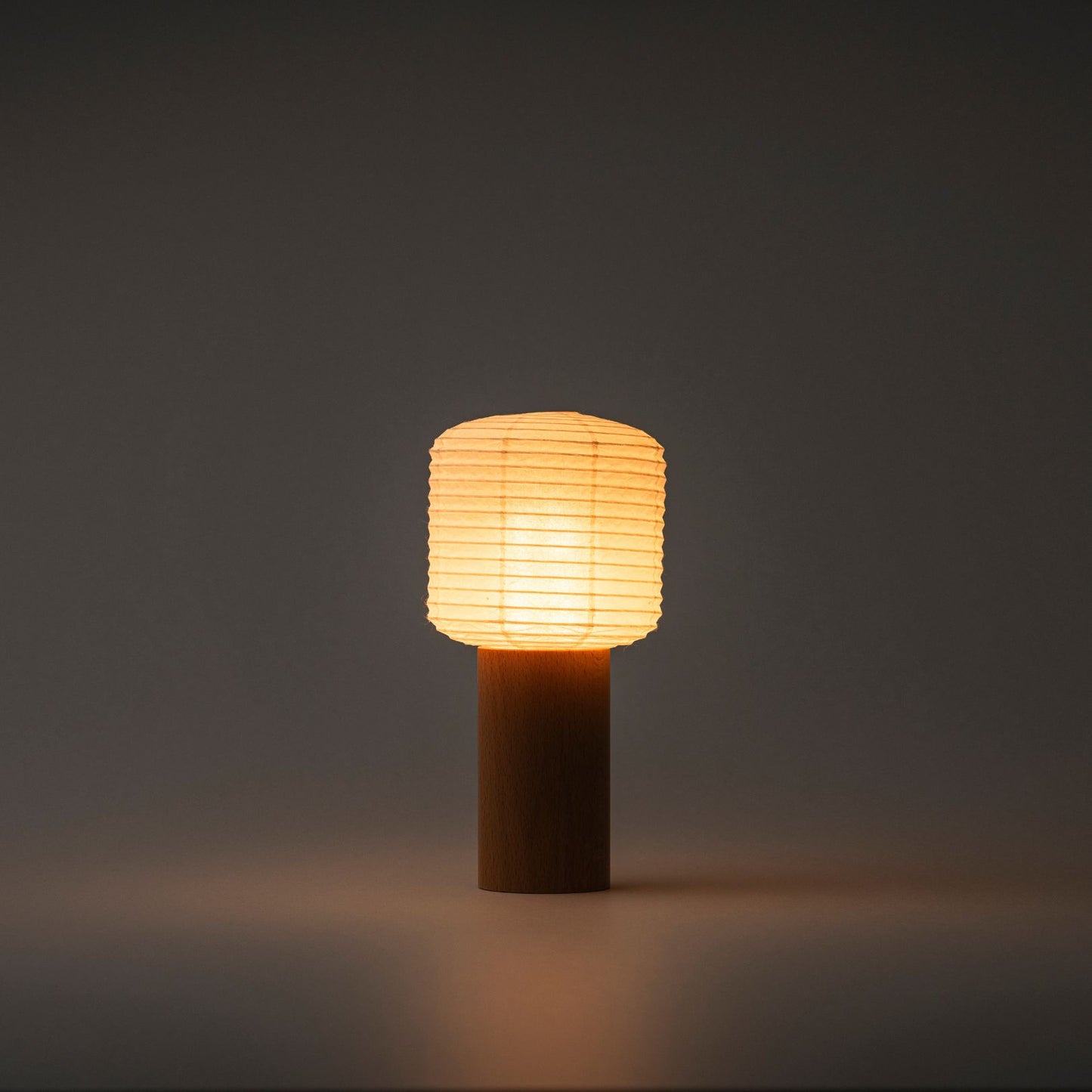 A portable Yame lantern with a wooden base and paper top, emitting bright warm light in a dark room
