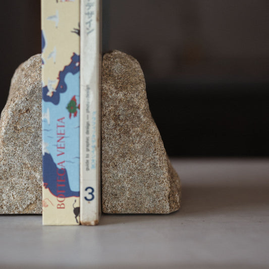 Close-up shot of a handcrafted Japanese Aji stone bookend holding several minimalist design books together.