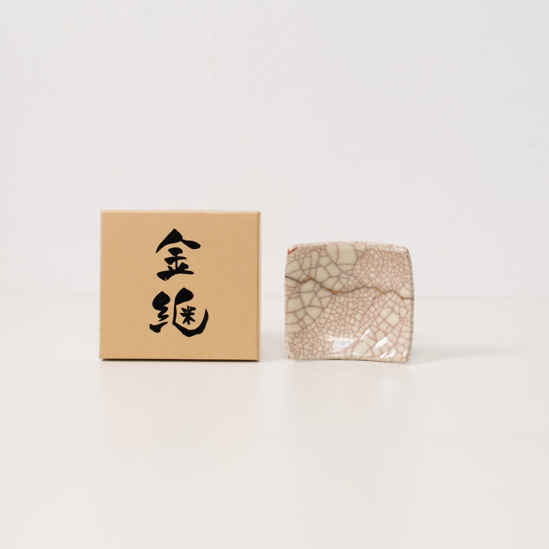 hvid kintsugi-tallerken hviler ved siden af en japansk gaveæske med kalligrafi, der viser wabi sabi-kunst