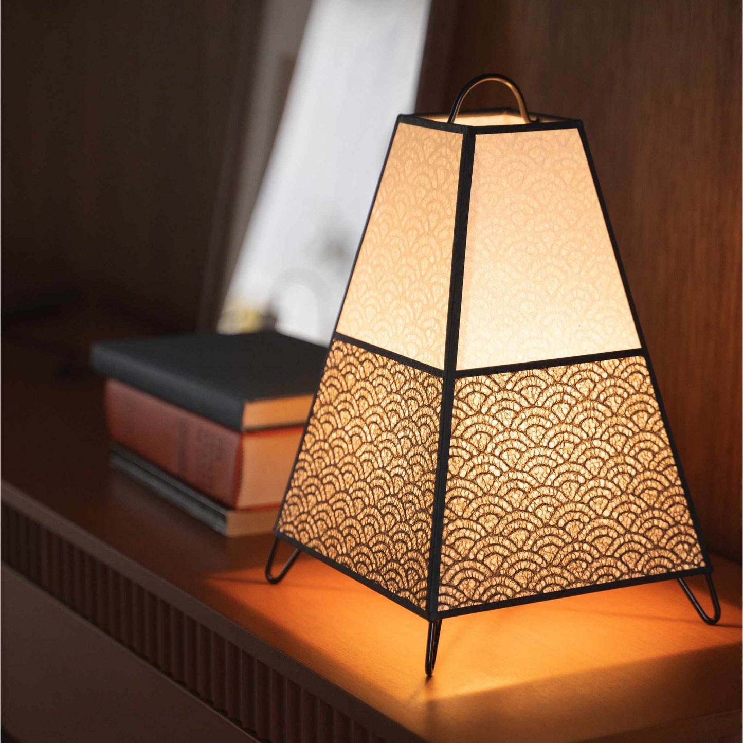 Close-up of a lit Japanese paper lamp KURA Small on a console table, highlighting the delicate Seigaiha lace paper.