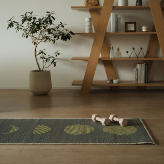 Japanese Tatami Yoga Mattress "Moon" Gray in a stylish Japandi living room, with small pink-beige dumbbells on top, setting a modern scene for home workouts and meditation.