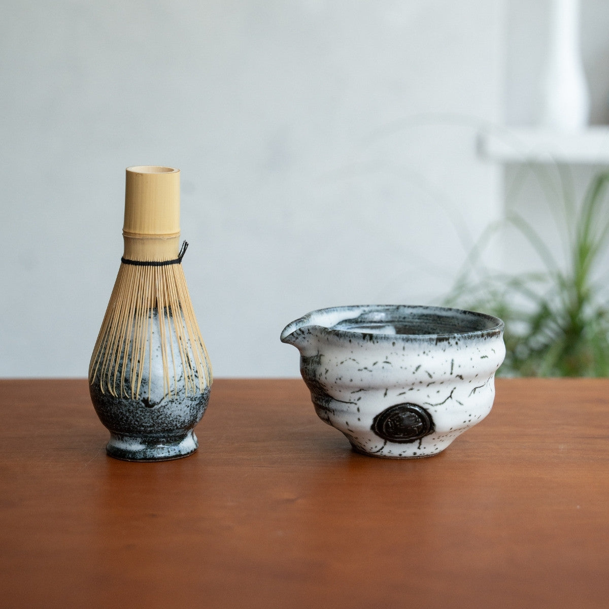 Bol à matcha Creative Cloud et fouet à matcha japonais sur un support, posés sur une table en bois pour sublimer votre rituel de thé matinal