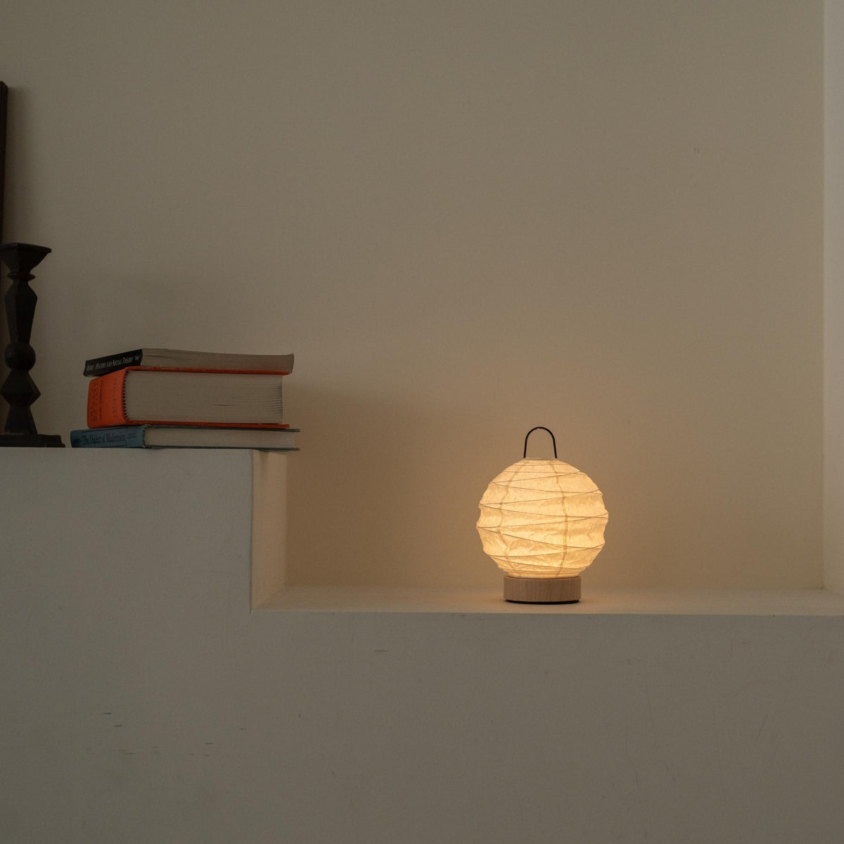 Ronde Japanse papieren tafellamp "Yuhi" met een zachte gloed als sfeerverlichting op een witte console in Japandi-stijl.
