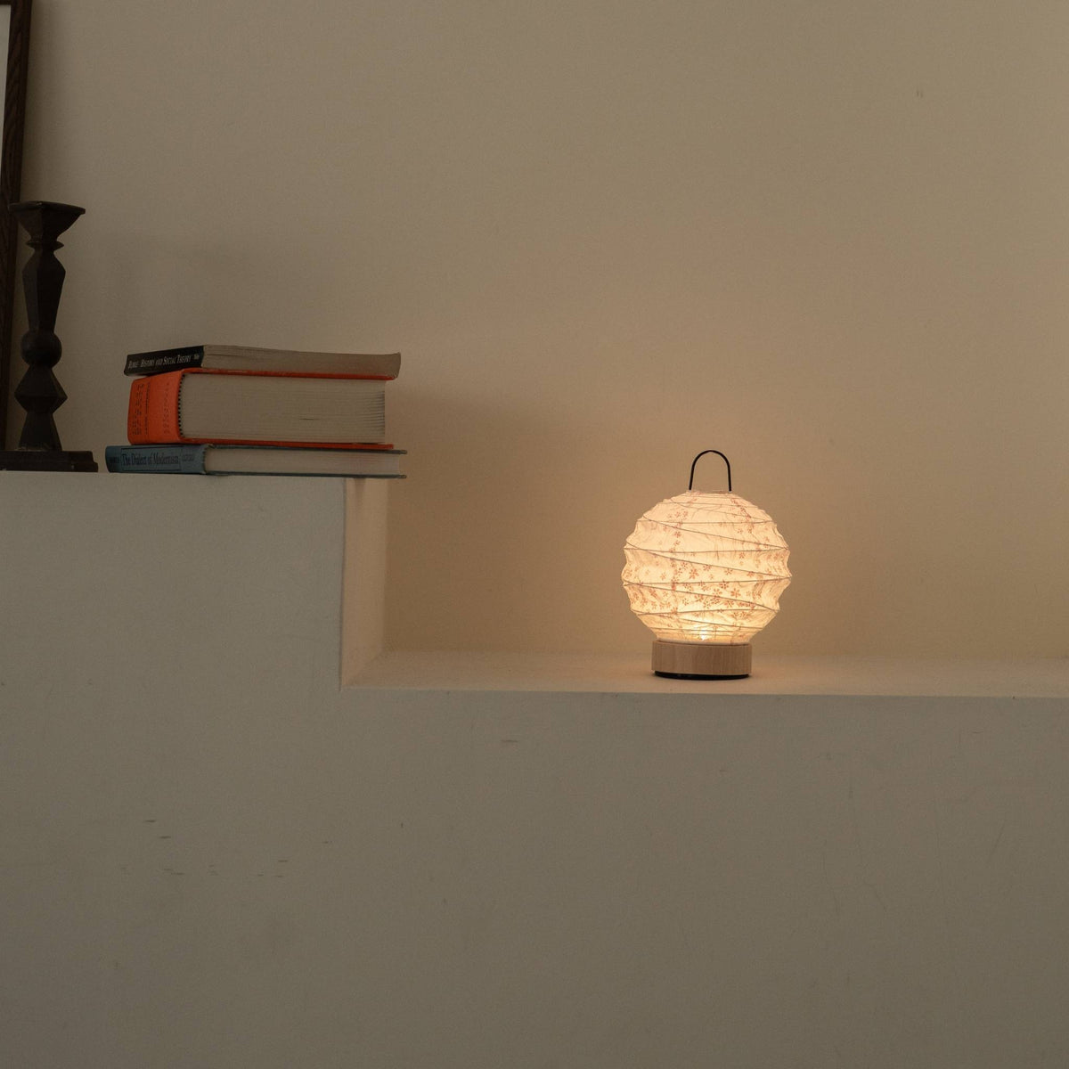 Lit ronde Japanse papieren tafellamp "Yuhi" Sakura die een zacht licht werpt als sfeerverlichting op een witte Japandi-stijl console.