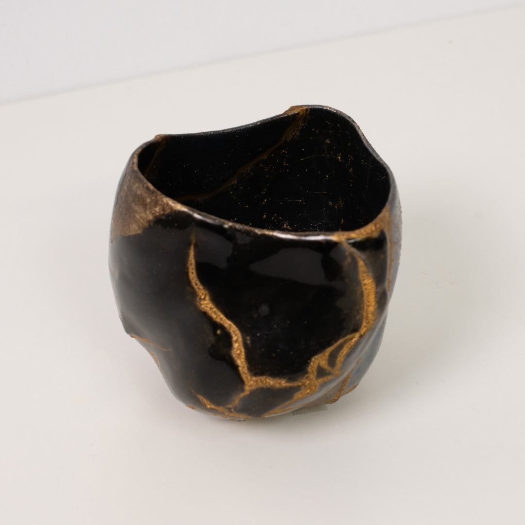 High angle view looking into a black kintsugi matcha bowl revealing thick gold repairs of wabi sabi art
