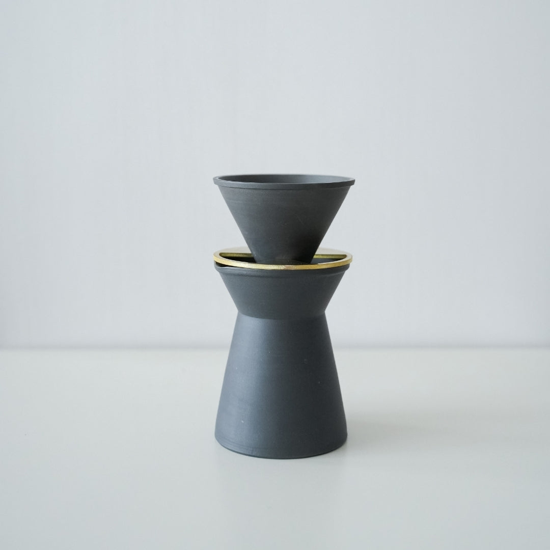 "Un ensemble de cafetière et de filtre Banko ware minimalistes noirs et blancs sur une table de cuisine en bois."
