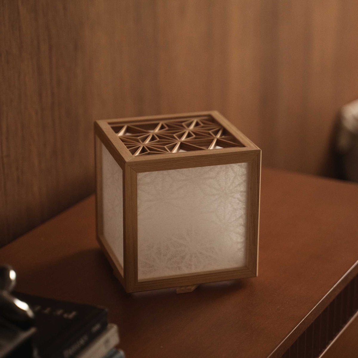 Quadratische japanische Kumiko-Laternenabdeckung, von innen beleuchtet, die die Asanoha-Muster-Silhouette in einem japanischen Schlafzimmer zeigt