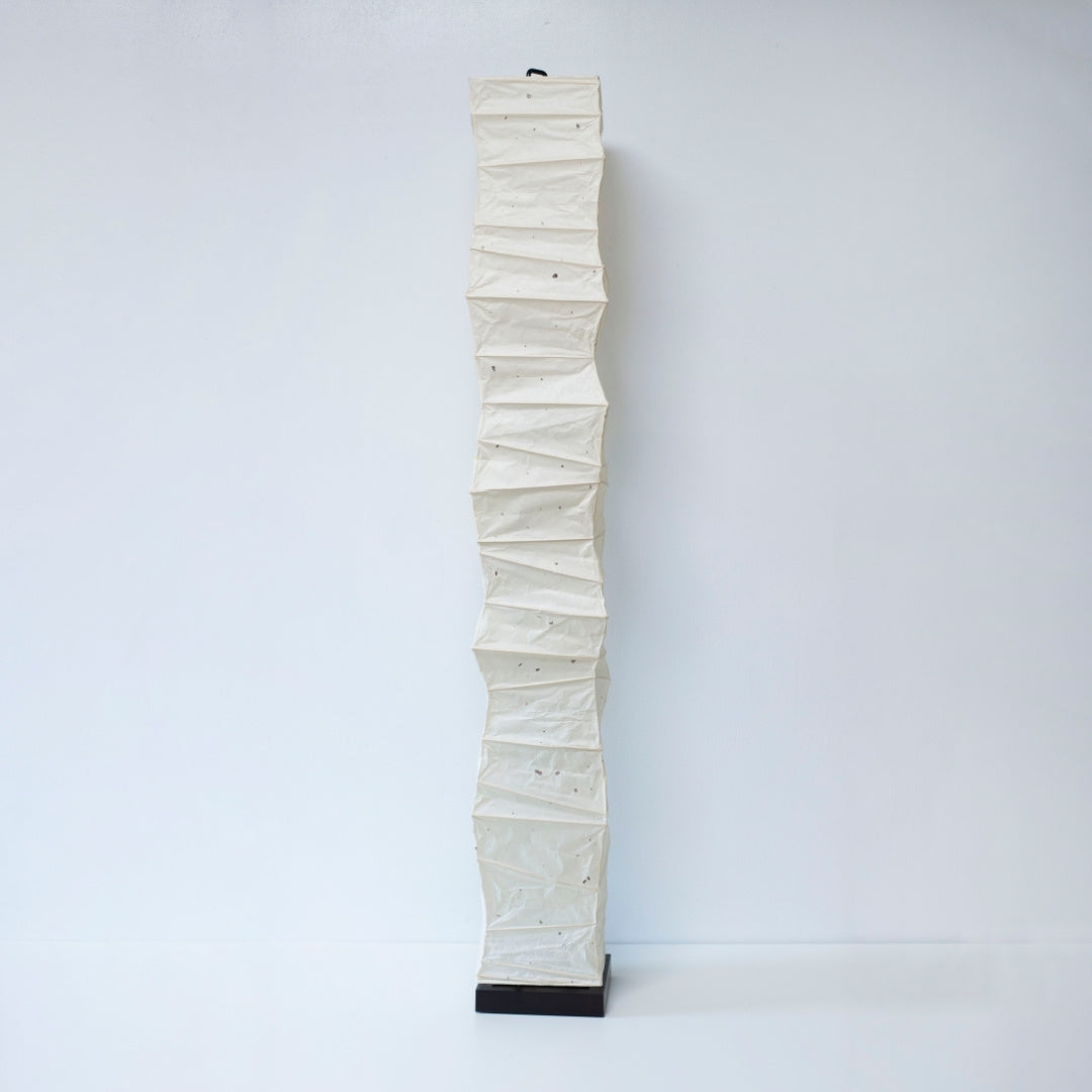 Full view of a tall, randomly curved Japanese washi paper lamp on a white background