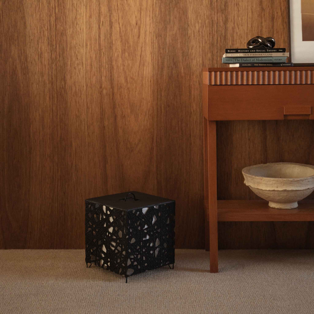 Cube shaped black paper floor lamp Me-Look 03 standing on a beige carpet against a dark wooden wall in a living room
