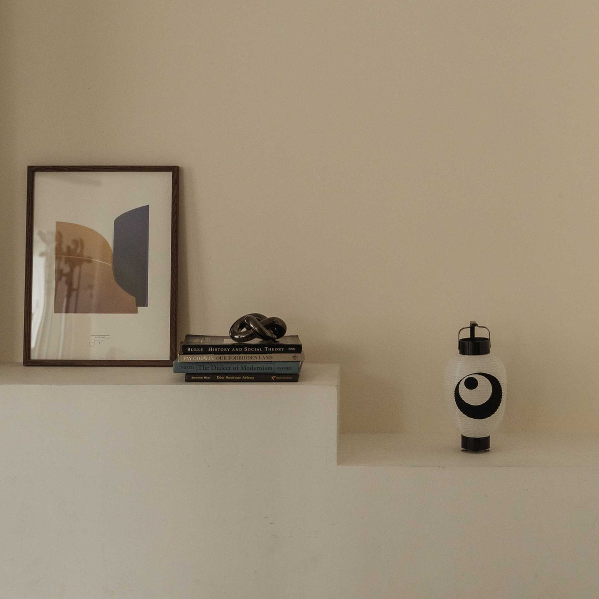 A unique moon and star Japanese paper lantern glowing warmly on a white ledge in a calm minimal home setting.