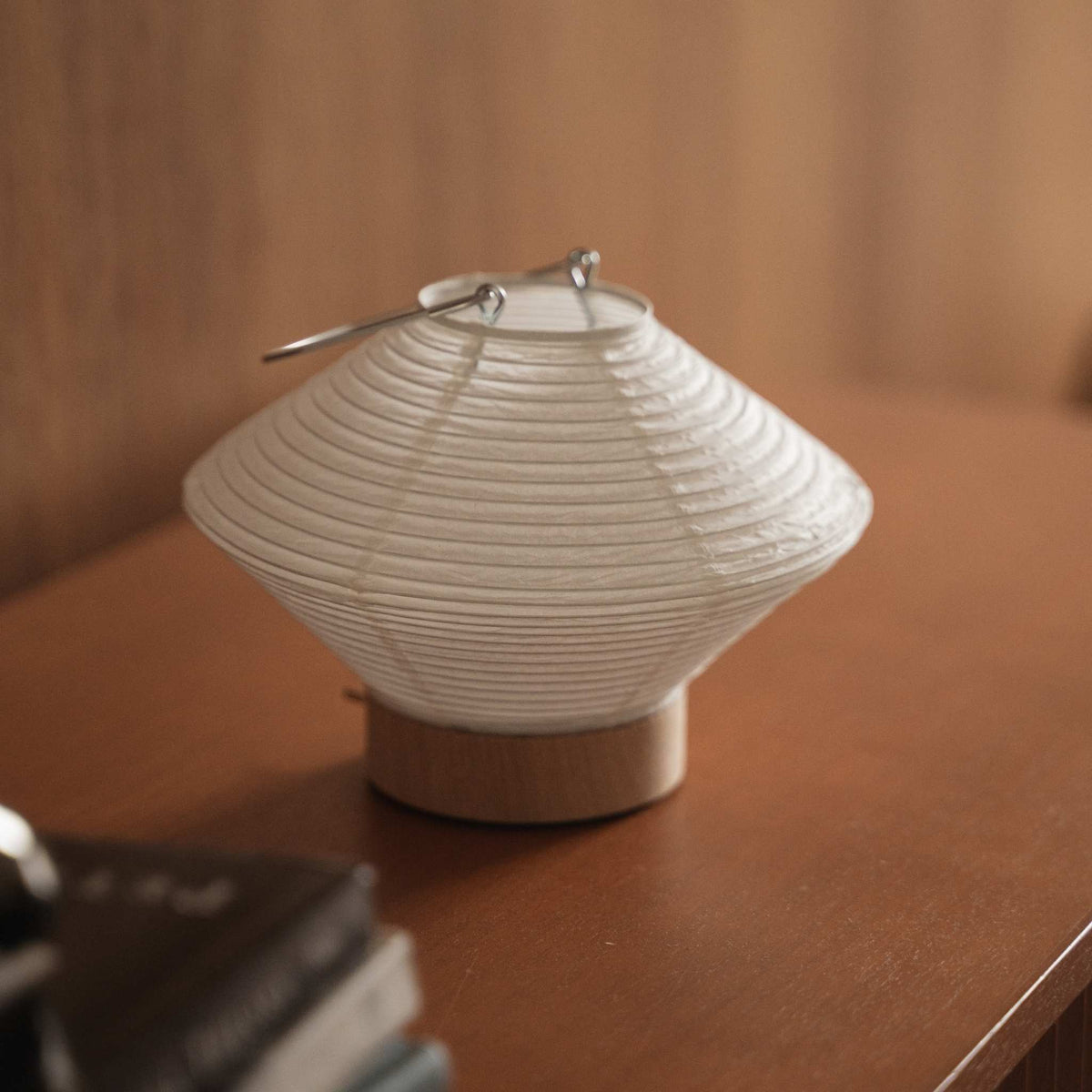 Lille japansk papir bordlampe Rin 05 stående på et brunt konsolbord i træ, der viser dens runde hvide form