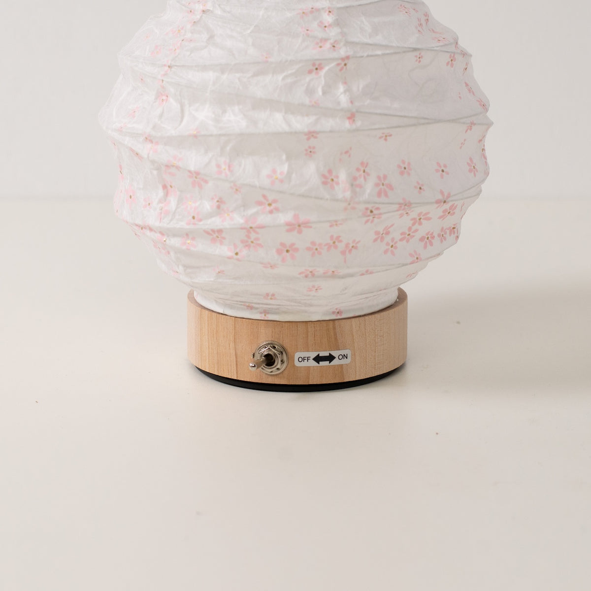 Japanse Papieren Tafellamp "Yuhi" Sakura, wit, close-up van de houten voet en tuimelschakelaar voor de draadloze lamp.