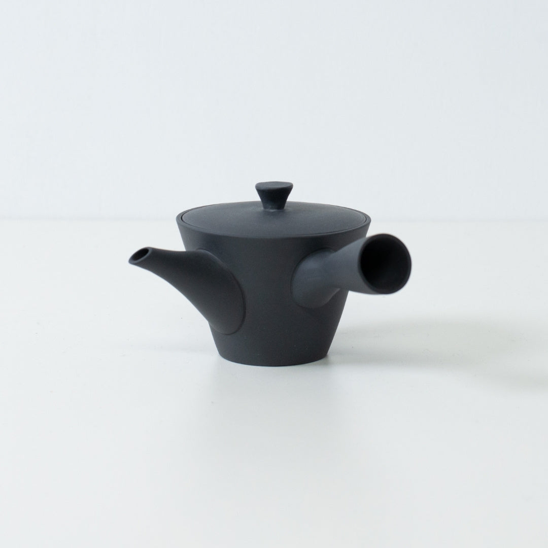 Zijaanzicht van een zwarte, ongeglazuurde Japanse theepot (sencha kyusu) met een compact banko yaki kleidesign en tuit.