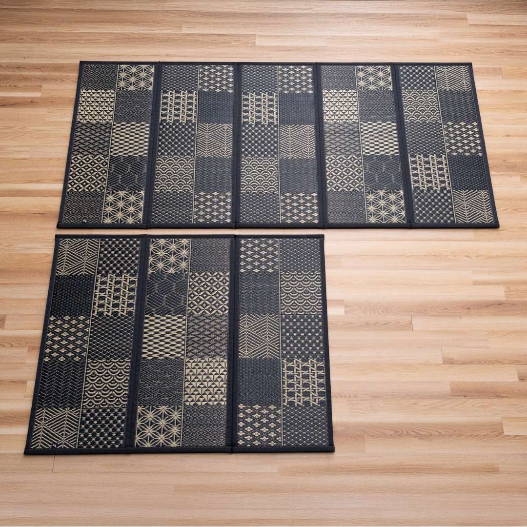 Black Edokomon tatami mattresses in 3 and 5 panel foldable sizes laid out on a wooden floor for modern Japanese decor.