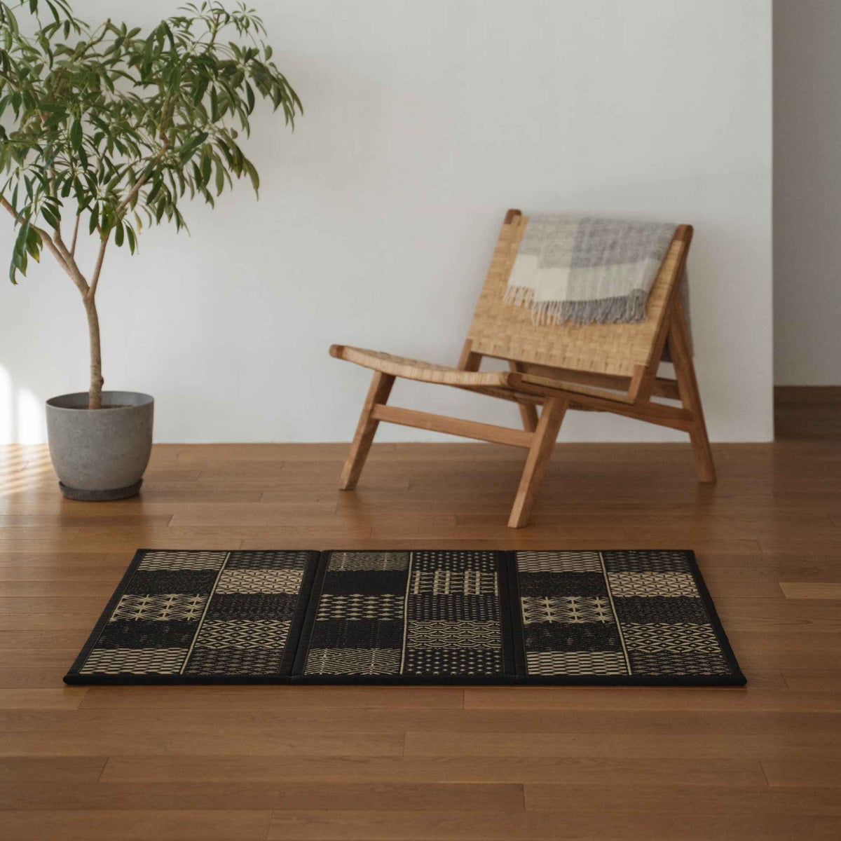 Three panel black tatami mat with edokomon patterns laid on a wooden living room floor for modern japanese decor.