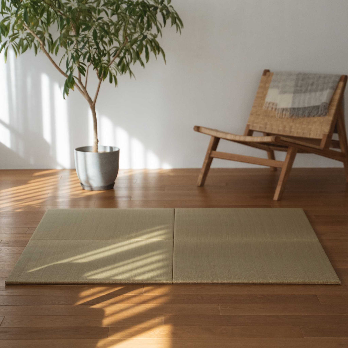 Four square tatami mat panels laid on a wooden living room floor creating a natural zen decor corner.