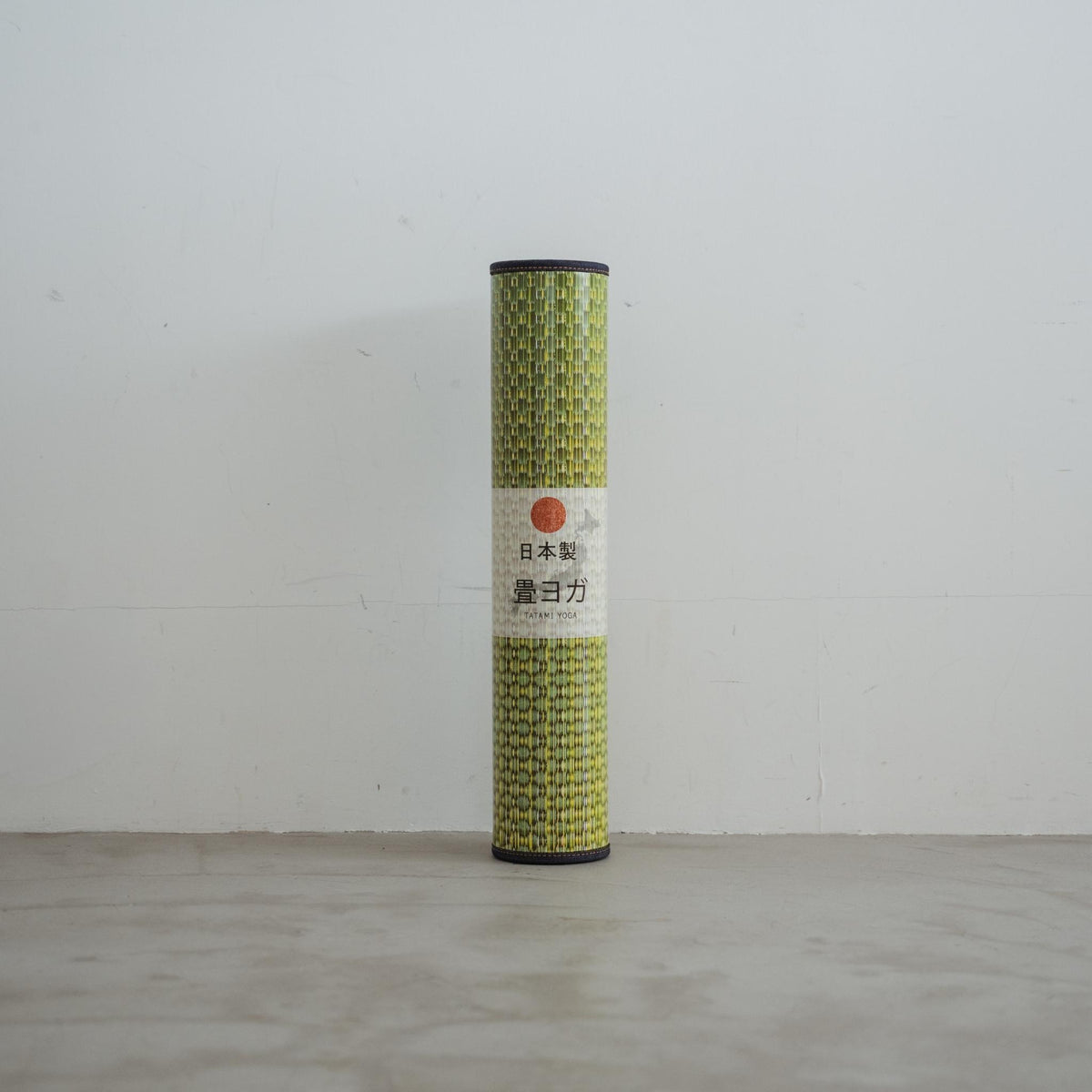 Vertical rolled green tatami mat package standing on a concrete floor evoking a natural vibe for japanese decor.