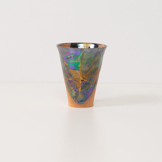 An authentic kintsugi cup stands alone highlighting colorful metallic glazes that define this beautiful kintsugi pottery