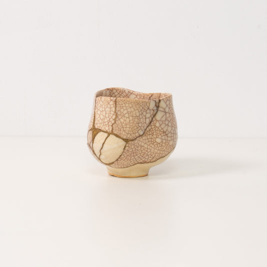 A white kintsugi matcha bowl rests beside a wooden box representing beautiful wabi sabi art and resilient pottery art