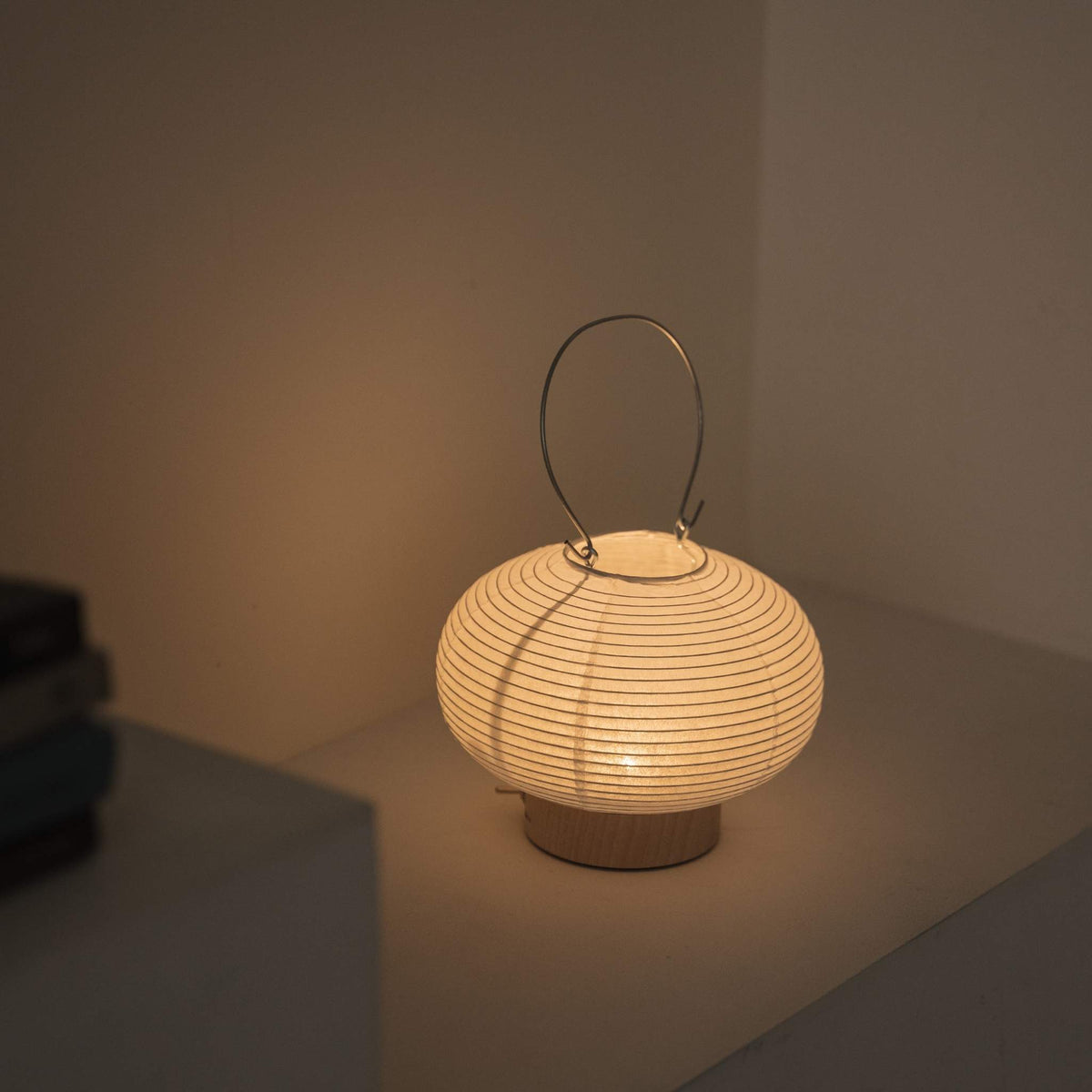 Overheadsbillede af en tændt bærbar lampe lavet af mino washi-papir, der fremhæver den ribbede struktur og det varme lys