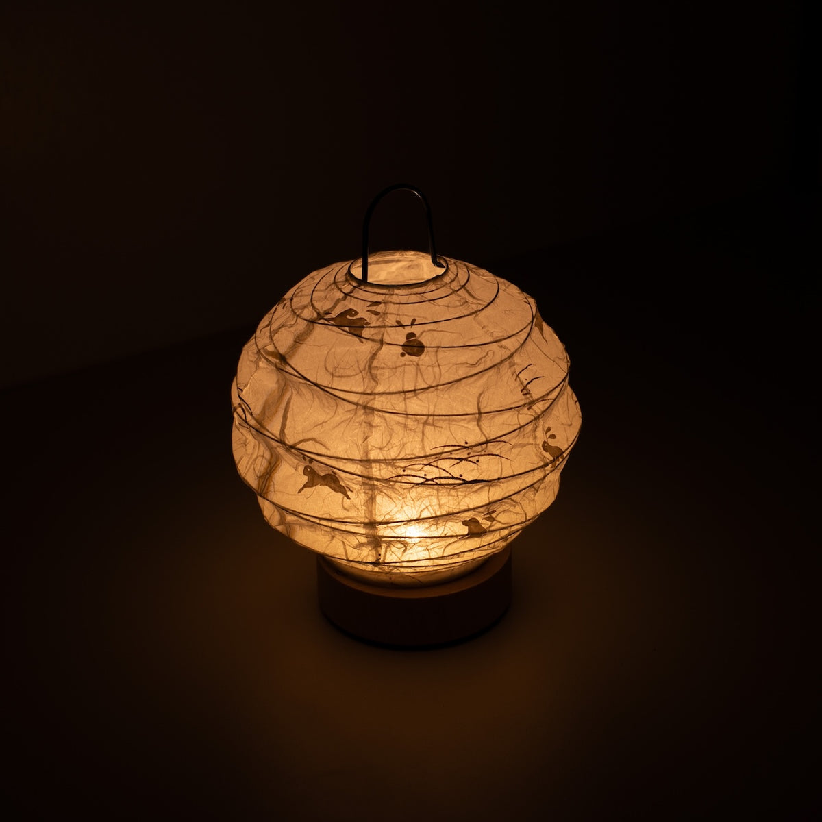 "Japanse Papieren Tafellamp \"Yuhi\" Konijn, wit, Mino Washi papier - aanzicht van bovenaf van verlichte lamp in Japandi-stijl met draadhandvat."