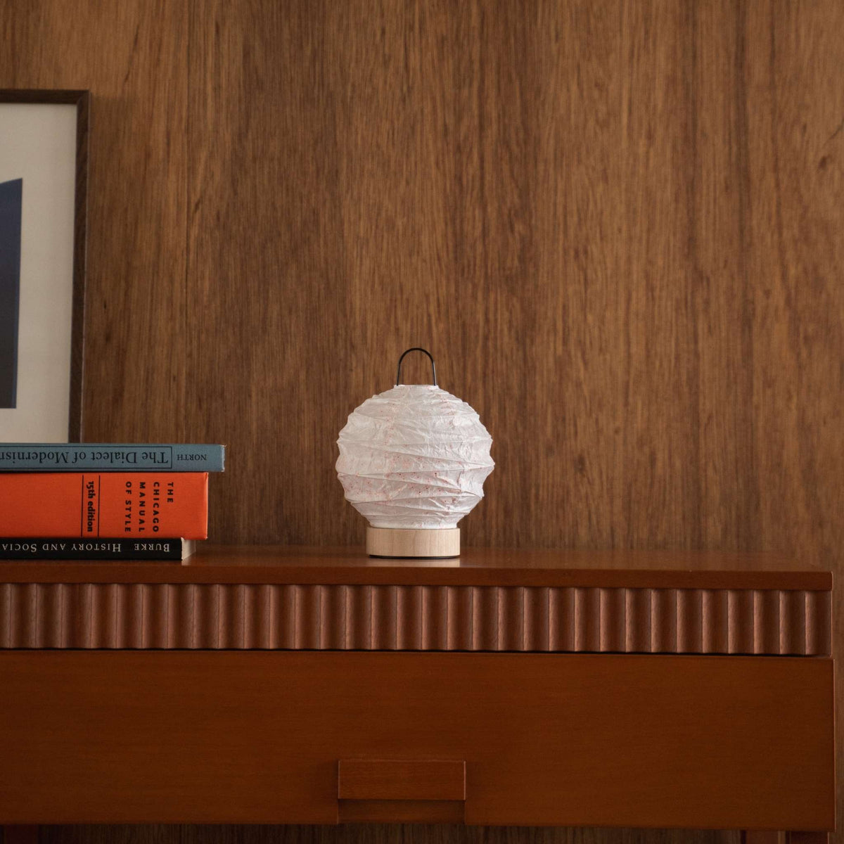 Onverlichte Japanse papieren lamp met sakura-patronen, gestyled op een houten console tafel in mid-century modern design.
