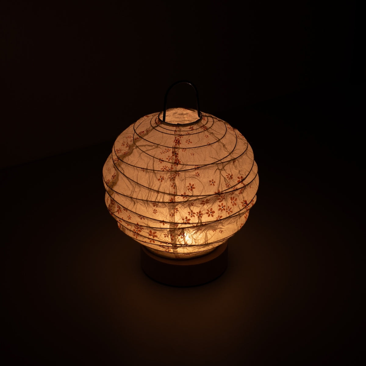 "Japanse Papieren Tafellamp \"Yuhi\" Sakura, wit, Mino Washi papier - hoge hoek weergave van verlichte Japandi stijl lamp met draad handvat."