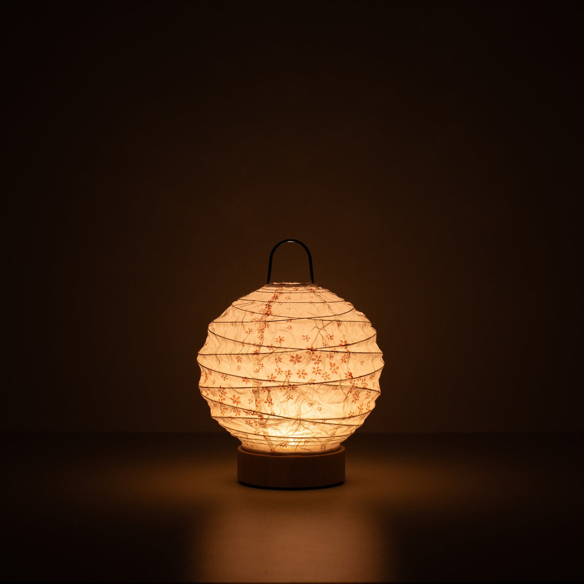 Japanse Papieren Tafellamp "Yuhi" Sakura, wit, Mino Washi papier - verlichte ronde papieren lamp die een warme gloed werpt in een donkere kamer.